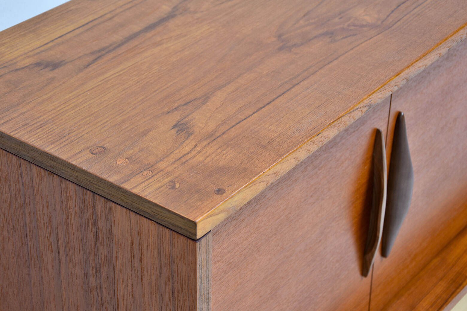 Enfilade vintage en teck scandinave avec poignées en bois foncé, style rétro, meuble de rangement élégant.