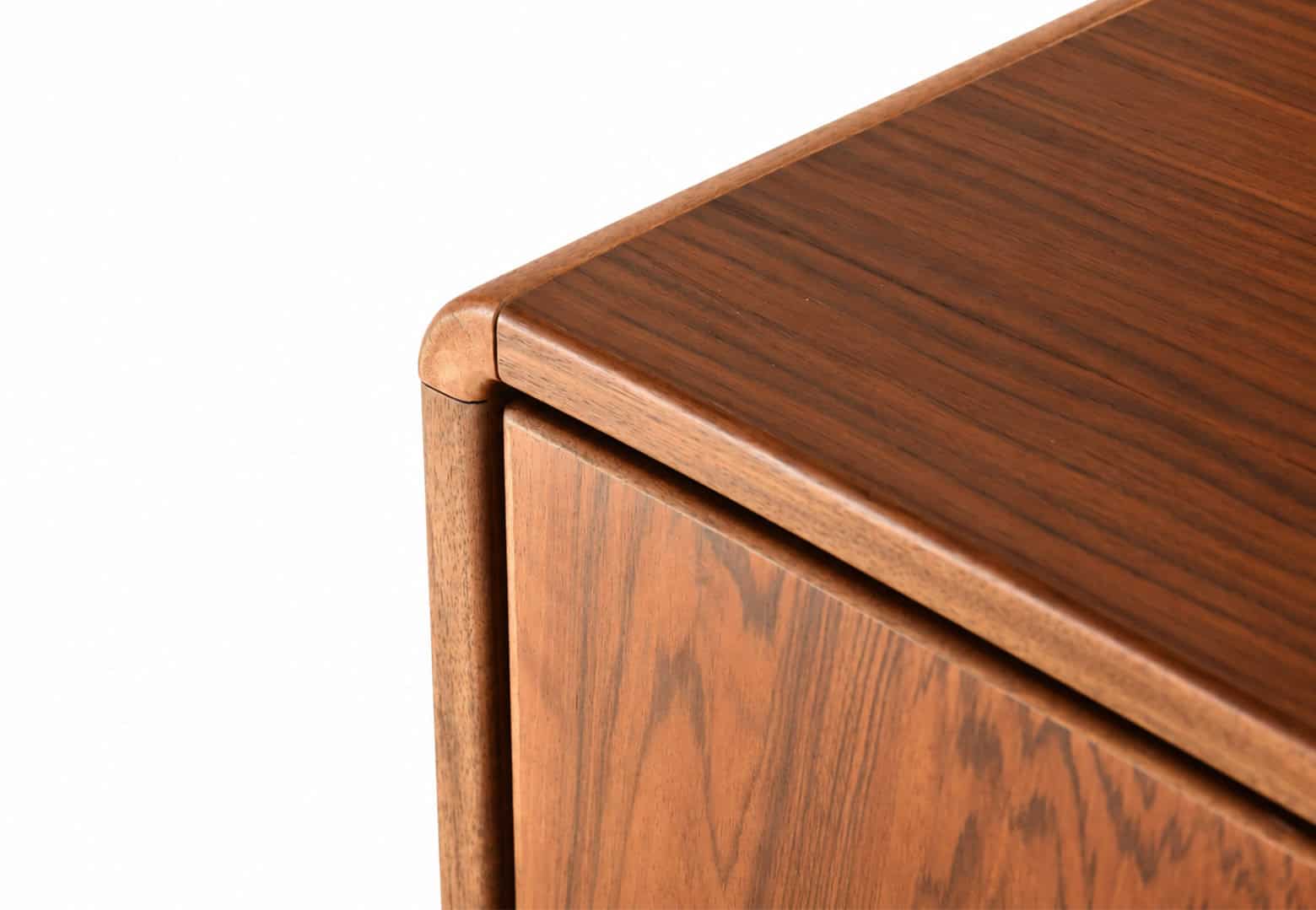 Détail d'une enfilade en noyer vintage restaurée, mettant en valeur la finition en bois naturel et le design scandinave.