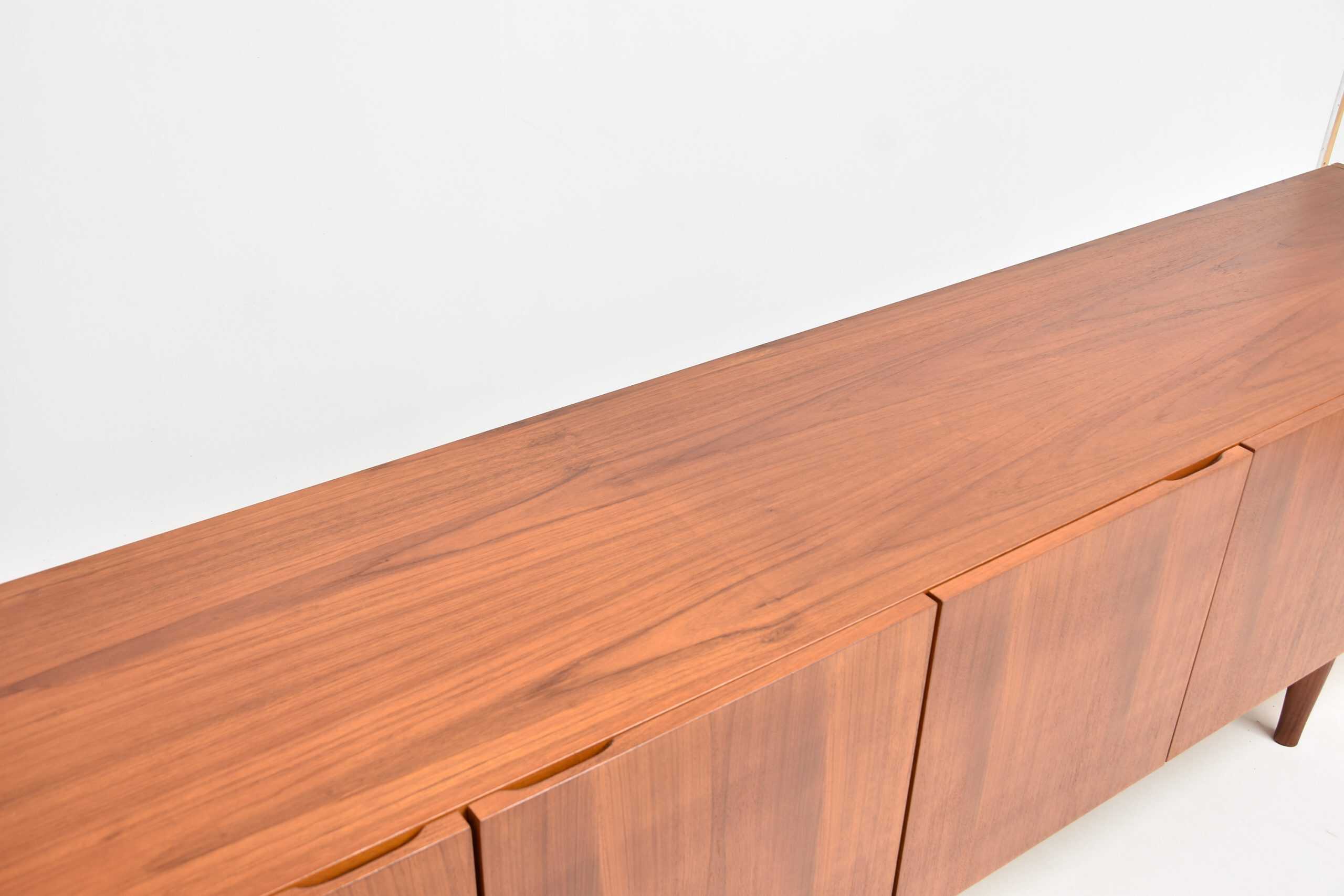 Enfilade scandinave vintage en teck restaurée, mettant en valeur le bois chaud et la finition soignée. Parfait pour un intérieur moderne ou rétro, alliant élégance et fonctionnalité.