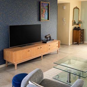 Enfilade vintage en teck naturel dans un salon moderne avec décoration élégante et mur bleu foncé.