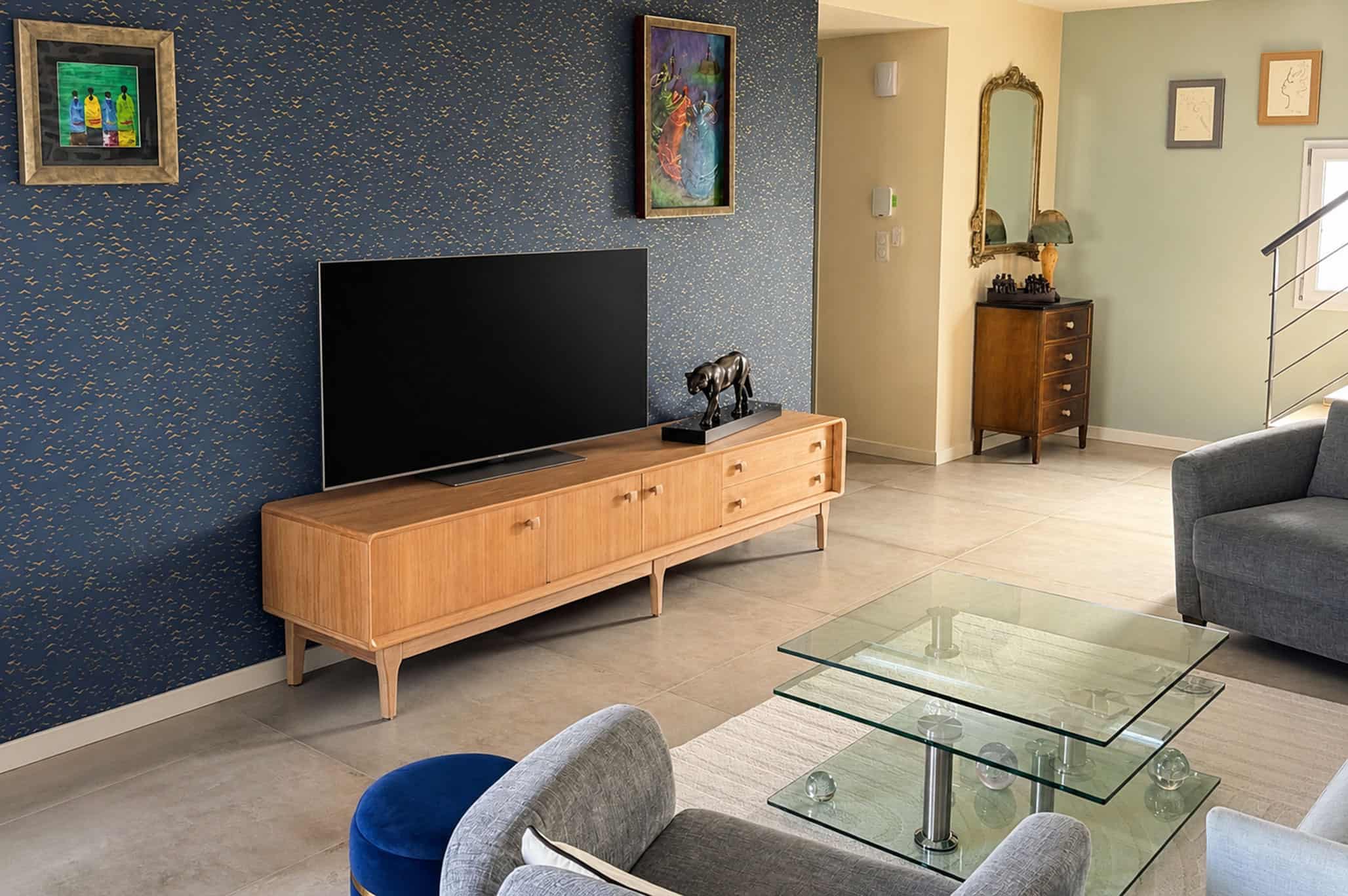 Enfilade vintage en teck naturel dans un salon moderne avec décoration élégante et mur bleu foncé.