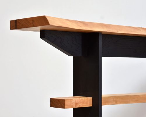 zoom sur une partie de meuble avec des pieds noir et un plateau en bois