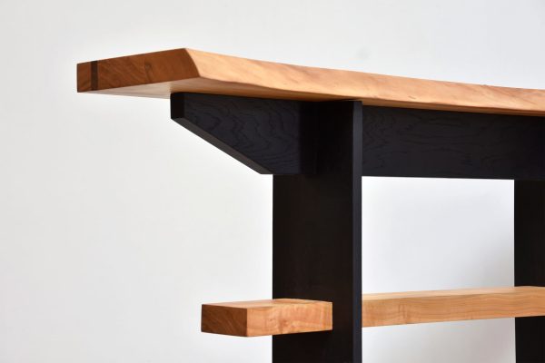 zoom sur une partie de meuble avec des pieds noir et un plateau en bois