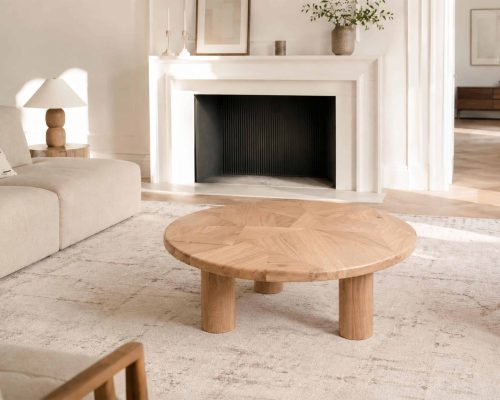 Table basse en bois massif dans un intérieur épuré avec cheminée blanche et décoration minimaliste.