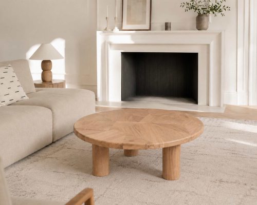Table basse en bois massif dans un intérieur contemporain avec cheminée et décoration minimaliste.